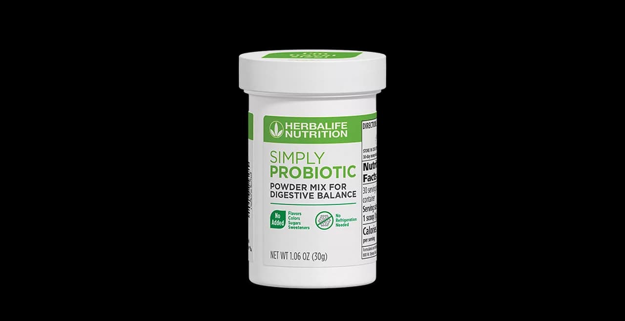 Boîte de Herbalife Simply Probiotic posée sur une table en bois à côté d'un verre d'eau